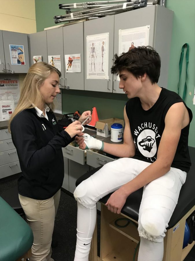 Henry Anderson ‘23 of the Oakmont football team gets his thumb taped up by Oakmont’s athletic trainer, Gianna Allen. 