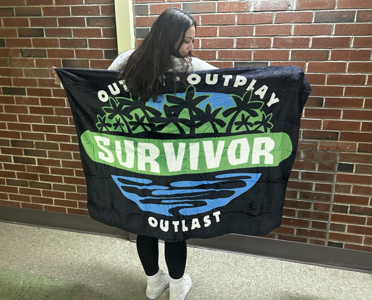 Senior, Aiyana Sanborn, holding up a Survivor blanket.