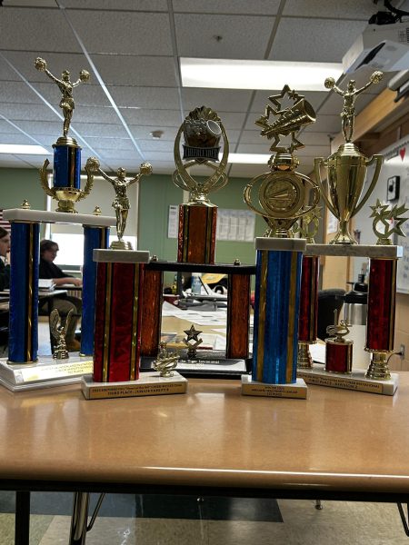 Coach Bergin flexes her trophies in her classroom