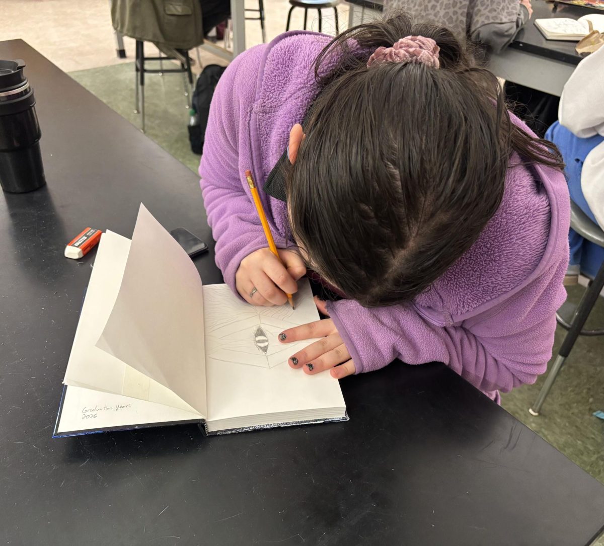 Senior Jillianne Gray sketching out ideas in her sketchbook.