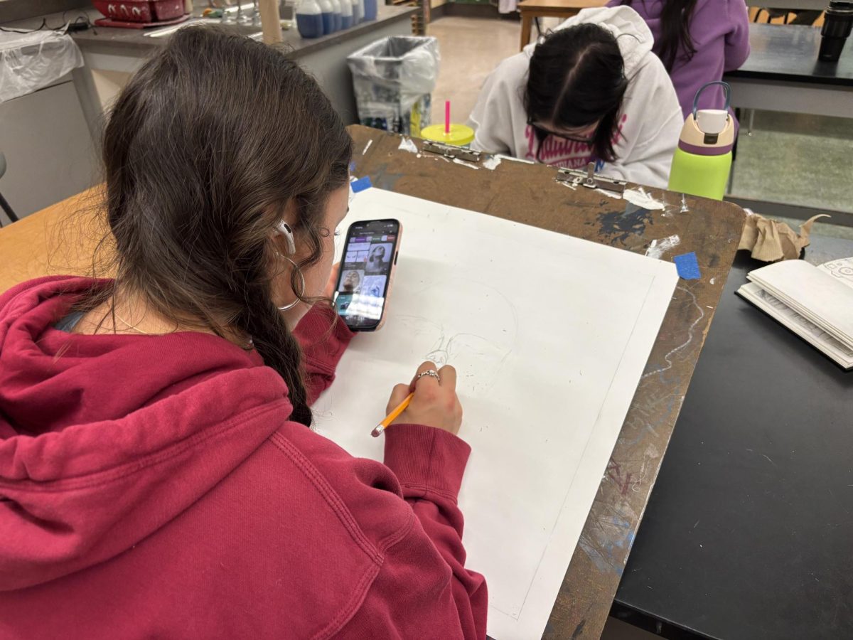 Junior Rosalie Tzilkowski using references to start a new drawing.