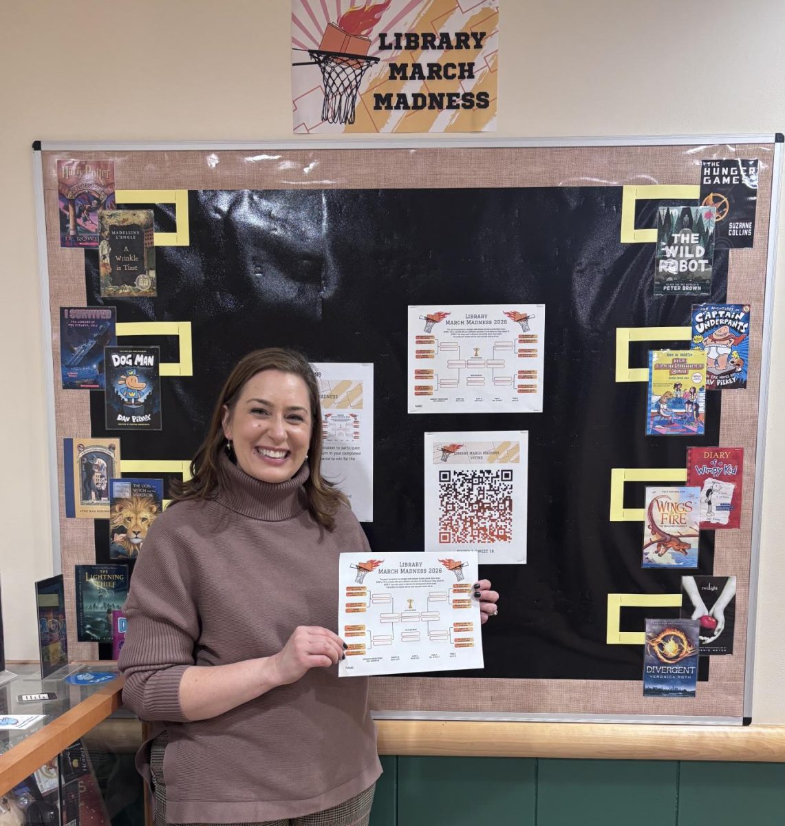Librarian Mrs. Jennifer Morin showing off the new March Madness bulletin board.