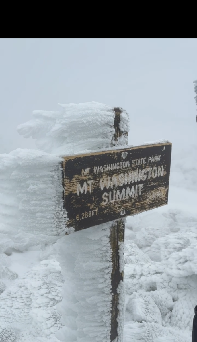 Ice accumulates on the summit marker due to high winds and freezing conditions.