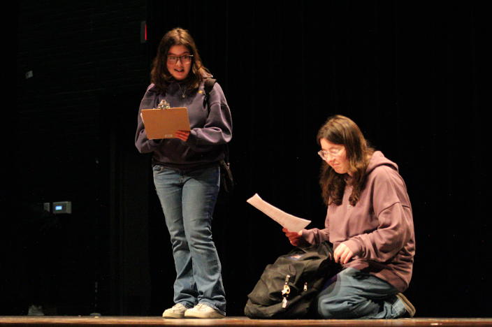 Two students going on a camping conversing with each other during March Madness performance. 
