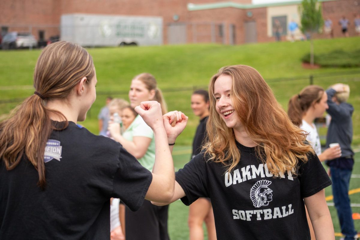 Juniors Olivia Martin and Katarina Pelkey fist bumping before their laps in the junior-senior relays.
