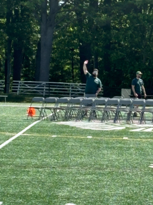 Head custodian Dave Wiita waving hi at the camera while setting up for senior graduation